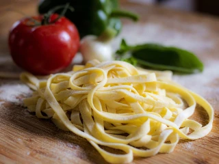 Surowy makaron tagliatelle na drewnianej desce