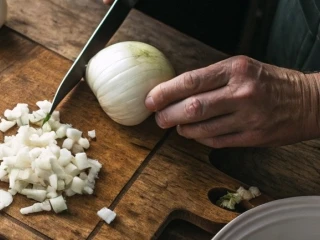 Mężczyzna kroi cebulę w kostkę