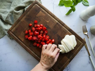 Pokrojone pomidorki koktajlowe oraz ser mozzarella na drewnianej desce