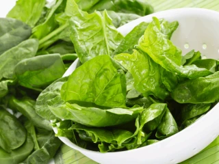 Świeży szpinak w białym durszlaku