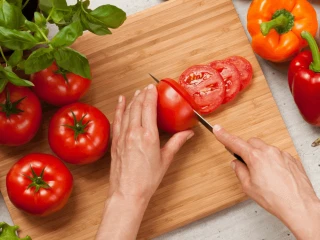 Kobieta kroi pomidory na drewnianej desce