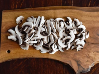 pokrojone pieczarki na drewnianej desce