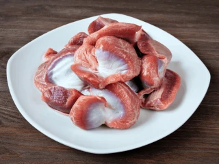 Surowe żołądki gęsie na białym talerzu