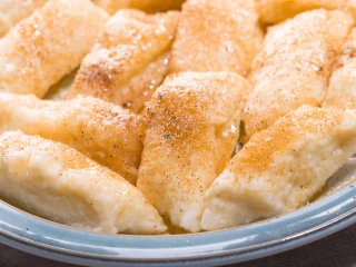 Pierogi leniwe obtoczone w brązowym cukrze na niebieskim talerzu