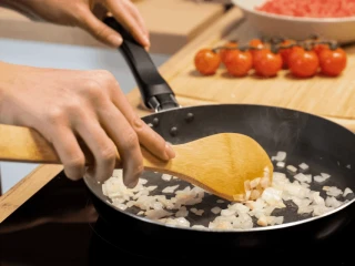 Kobieta podsmaża cebulę na patelni