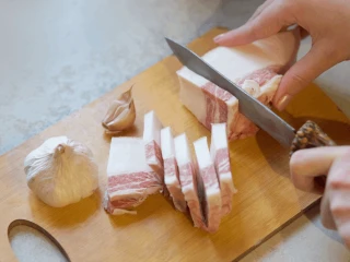Kobieta krojąca boczek na drewnianej desce