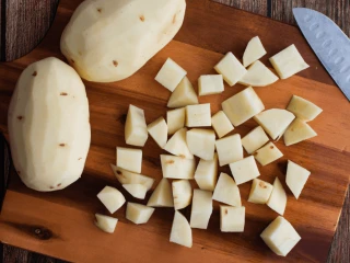 Pokrojone w kostkę ziemniaki na drewnianej desce