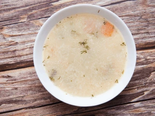 Talerz z zupą koperkową na drewnianym blacie