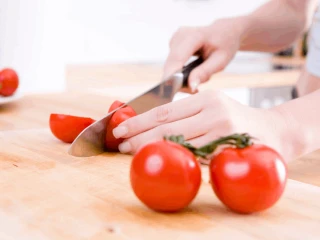 Kobieta kroi pomidory na połówki