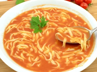 Biały talerz z zupą pomidorową z domowym makaronem