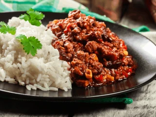 Chili con carne z ryżem podane na czarnym talerzu