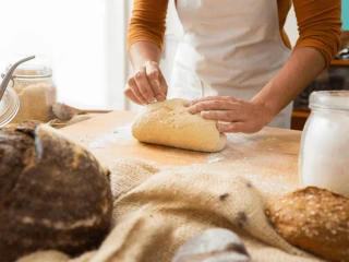 Osoba wyrabia ciasto na drewnianym blacie