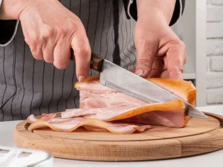 Osoba kroi boczek na drewnianej desce