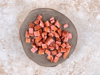 Kiełbasa pokrojona w kostkę na szarym talerzu