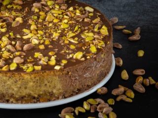 Sernik pistacjowy polany czekoladą i posypany pistacjami