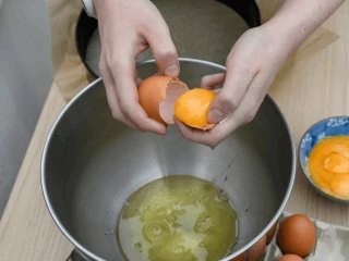 Zbliżenie na ręce kobiety oddzielającej białka od żółtek