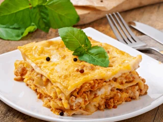 Lasagne na białym talerzu z warstwą sosu beszamelowego i mięsnym sosem bolońskim