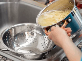 Zbliżenie na kobietę odcedzającą makaron