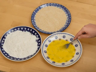 Trzy talerze z mąką, roztrzepanym jajkiem i bułką do panierowania kotleta schabowego