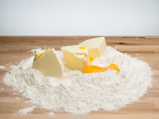 Składniki na ciasto na pierogi na drewnianej stolnicy