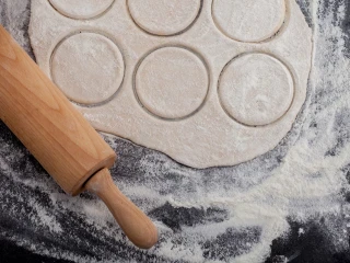 Osoba Zbliżenie na wykrojone kółka z ciasta na pierogi surowe pierogi na stolnicy