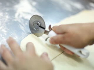 Zbliżenie na osobę krojącą ciasto francuskie na kwadraty
