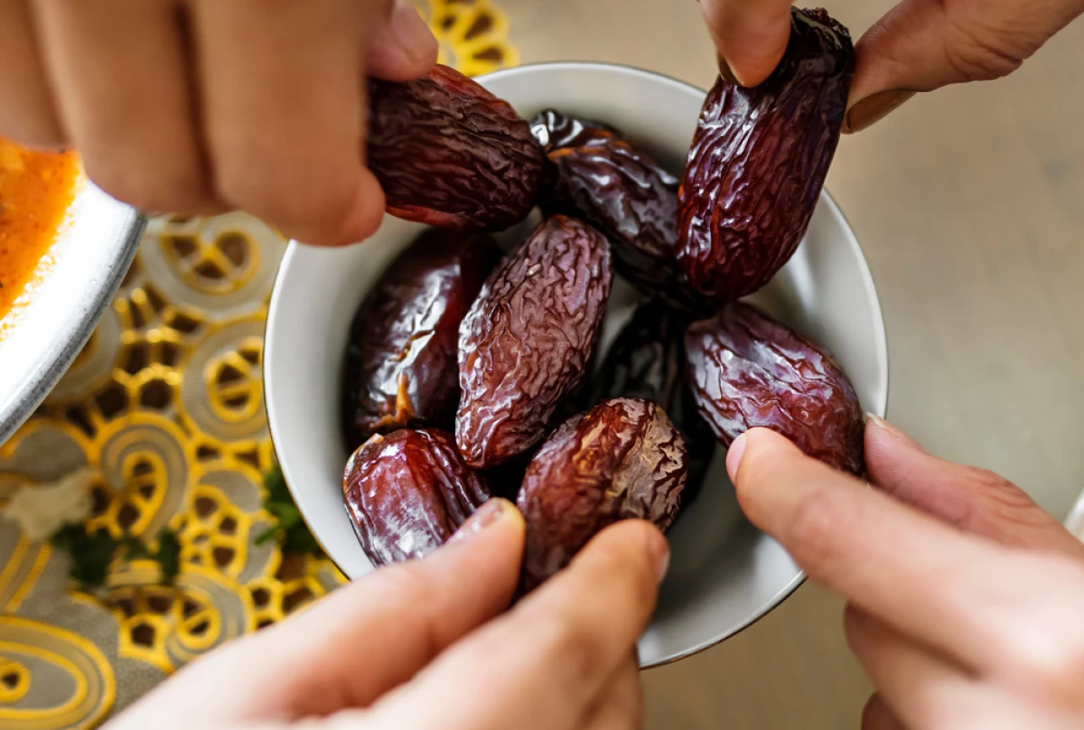 Cztery osoby trzymają w ręce daktyle nad białą miską