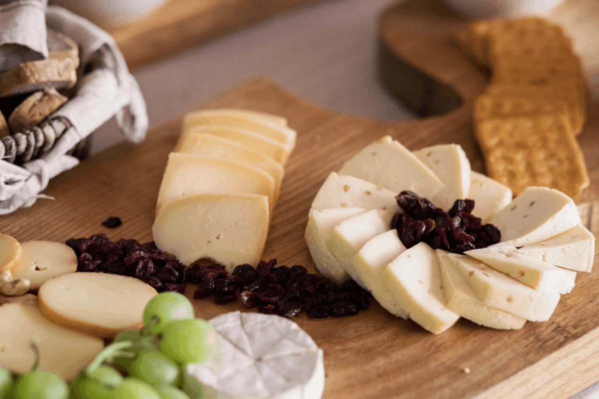 Deska serów z winogronami, żurawiną, krakersami i plasterkami sera na drewnianym stole