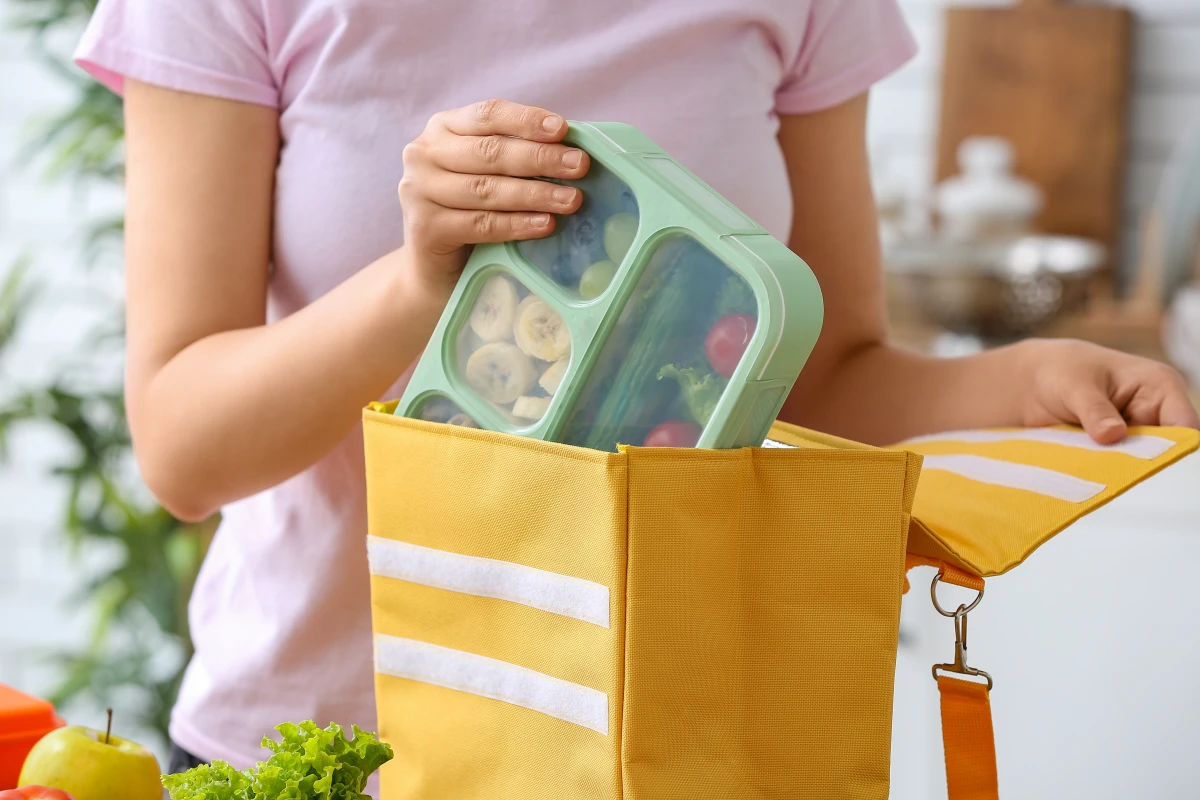 Dziewczynka pakująca lunch box do torby