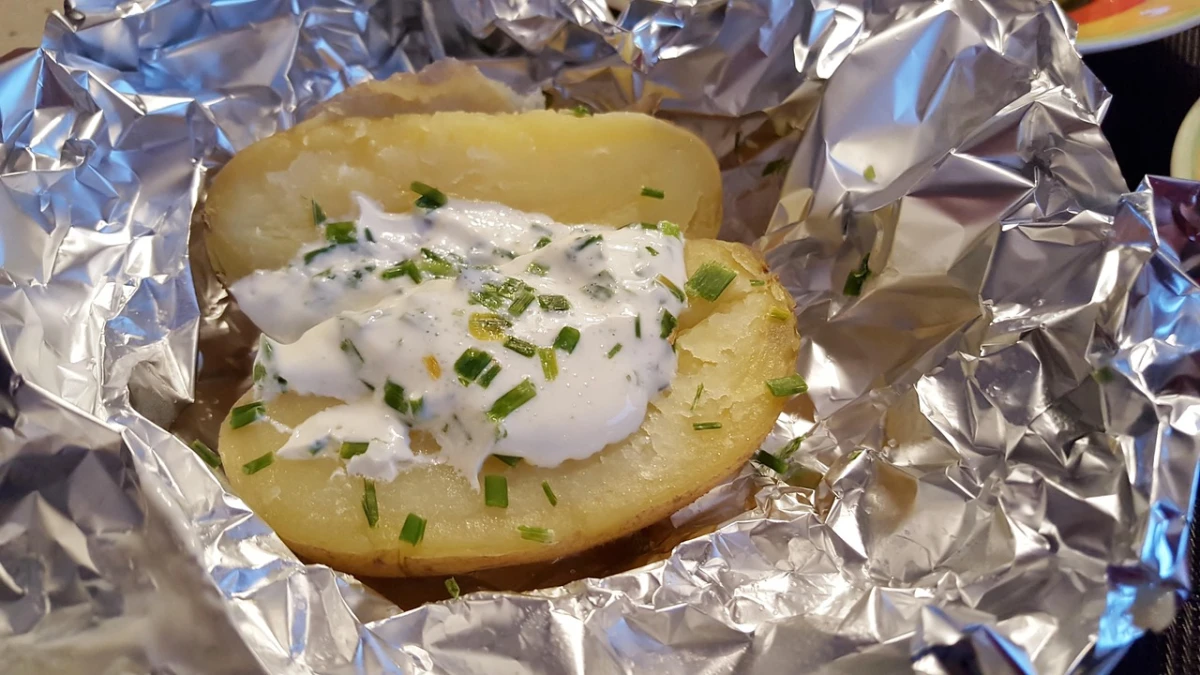 Grillowany w folii aluminiowej ziemniak z białym sosem i szczypiorem. 