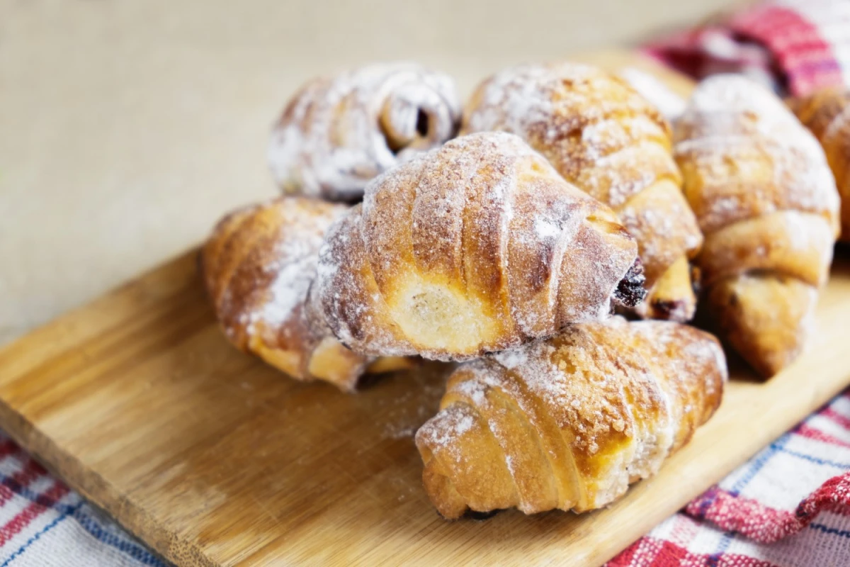 Słodkie rogaliki drożdżowe na drewnianej desce
