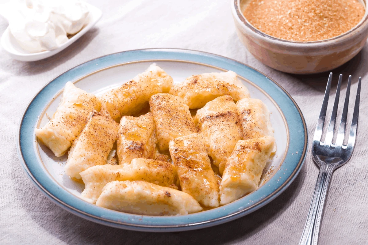 Kluski leniwe posypane brązowym cukrem na niebieskim talerzu