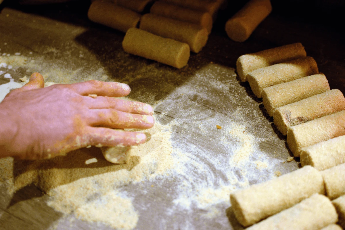 Mężczyzna obtacza krokiety w panierce