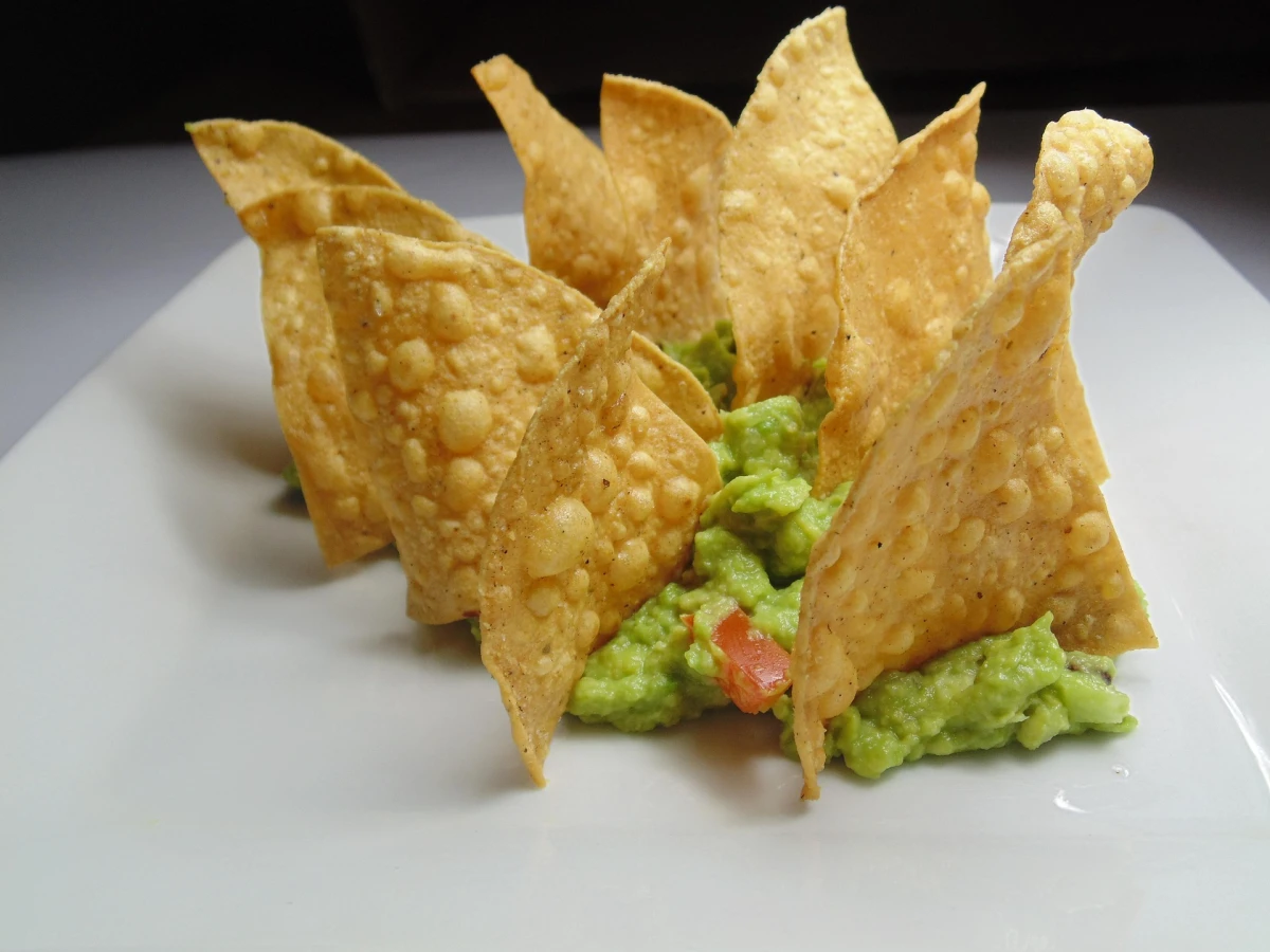 Nachosy z guacamole na białym talerzu. 