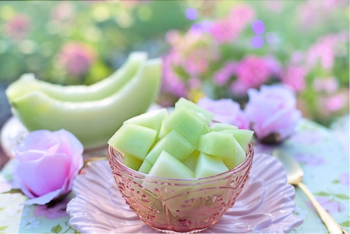 Pokrojony w kostkę jasnozielony melon miodowy leży w szklanej, ozdobnej misce