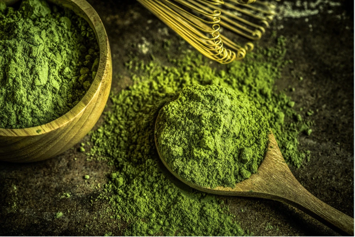 Proszek matcha na drewnianej łyżce i w misce
