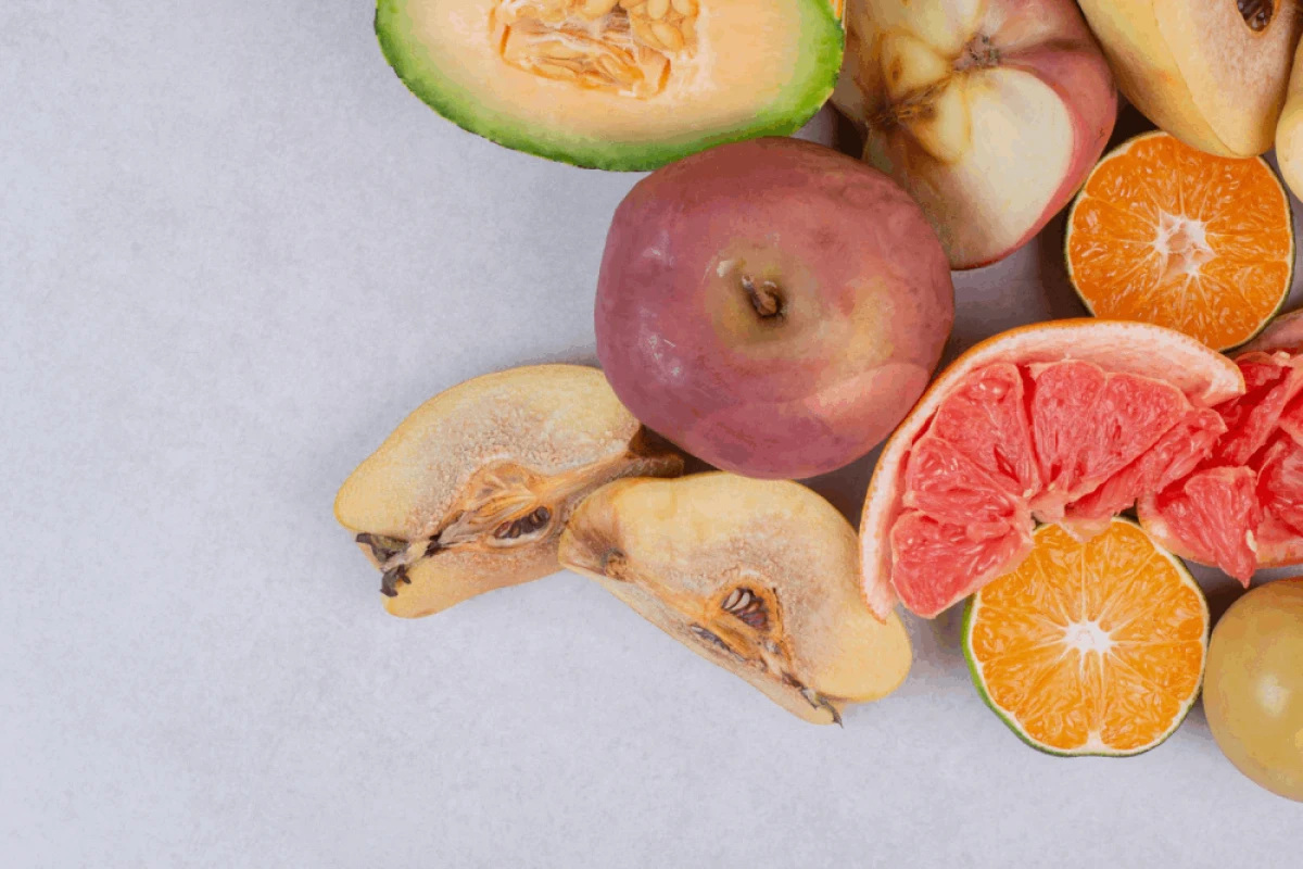 Przejrzałe owoce: jabłka, grejpfruty, limonki, mango na jasnym blacie