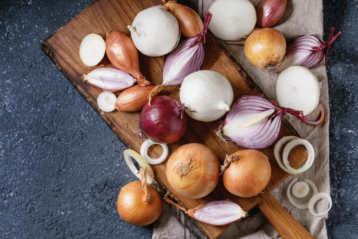 Różne rodzaje cebuli leżą na drewnianej desce