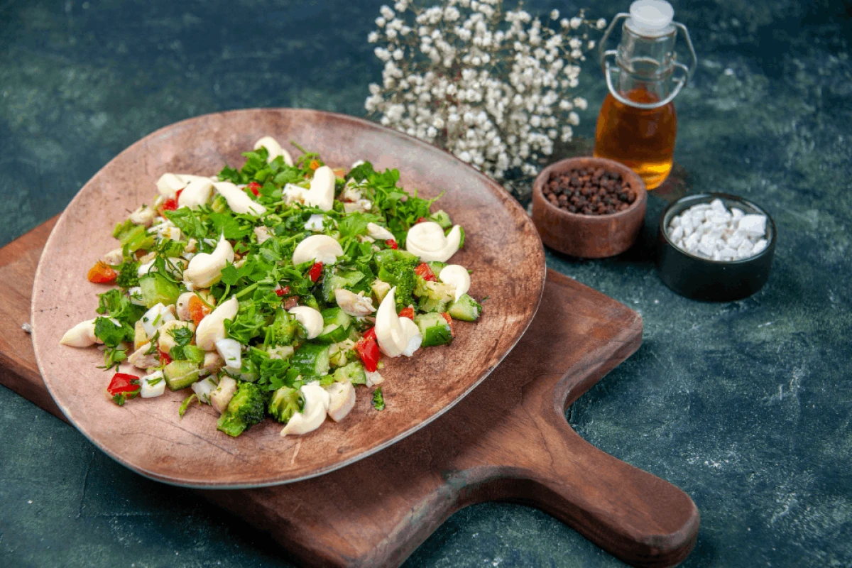 Sałatka z jarmużem i warzywami w ozdobnej misce na drewnianej desce