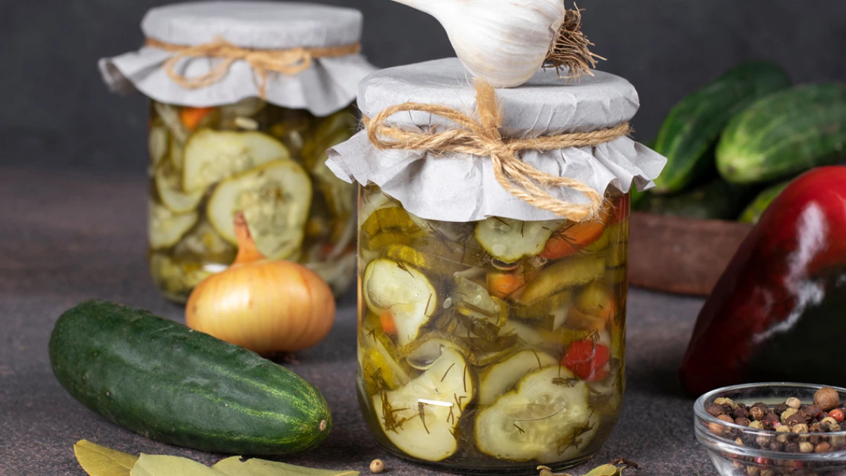 Sałatki warzywne w słoikach stojące na wiklinowym blacie w towarzystwie warzyw