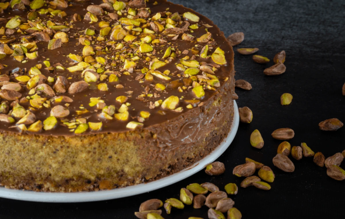 Sernik pistacjowy polany czekoladą i posypany pistacjami