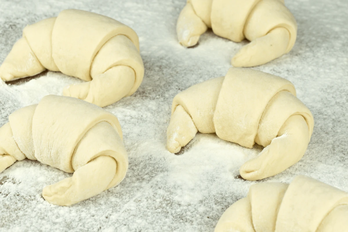 Surowe rogaliki ułożone na blacie - przygotowane i sformowane przed pieczeniem