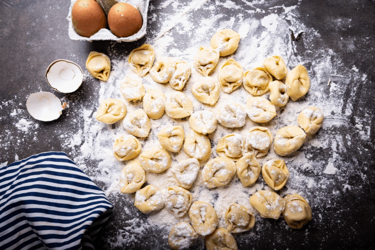 Ulepione uszka leżące na czarnym blacie w kuchni