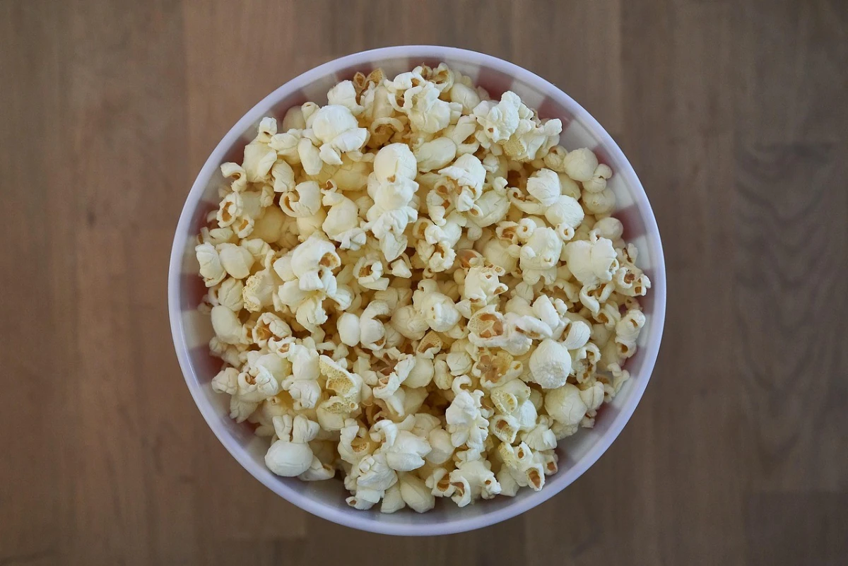 Widok z góry na miskę wypełnioną popcornem, ustawioną na drewnianej powierzchni