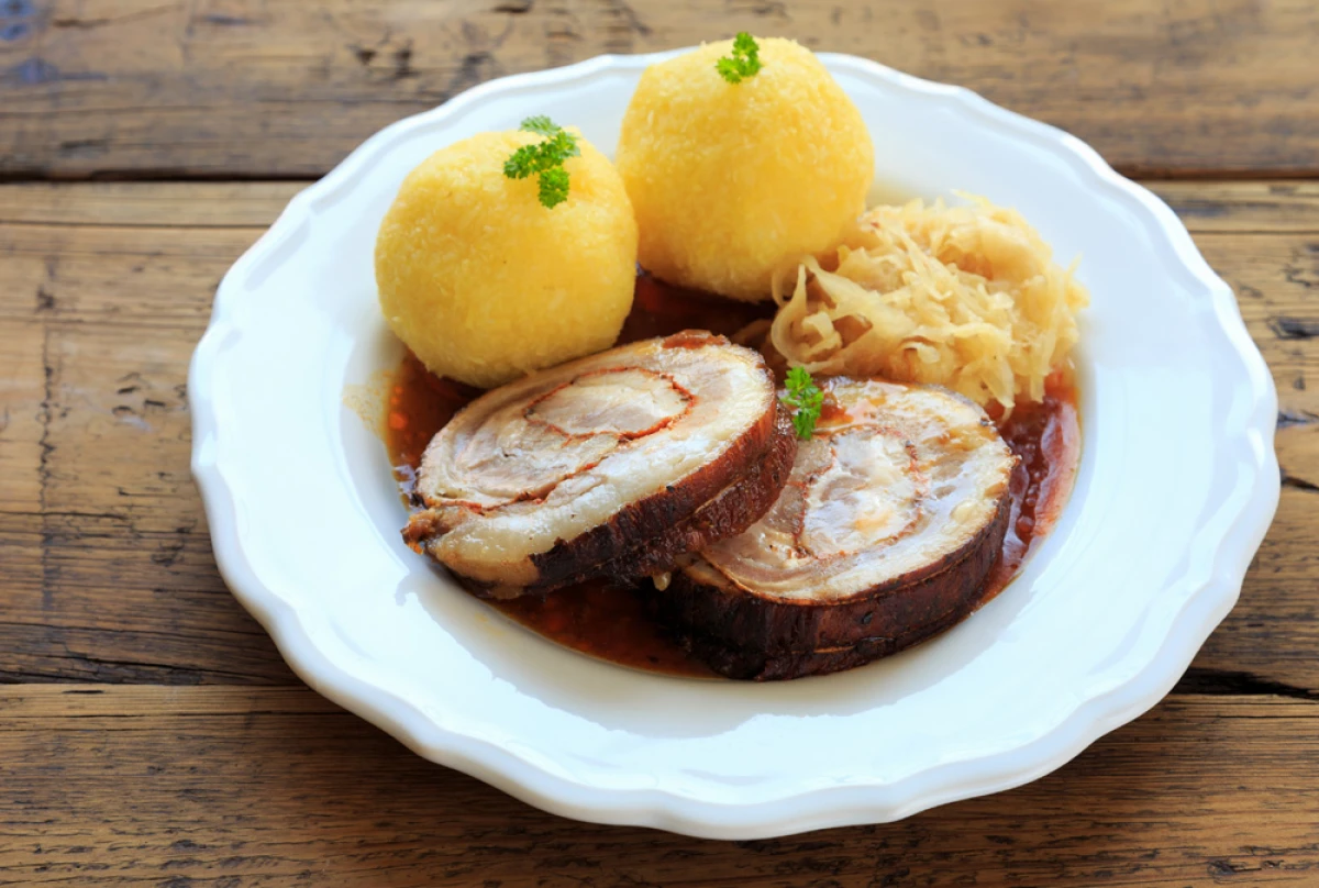 Wieprzowina z knedlikami i kapustą podana na białym talerzu