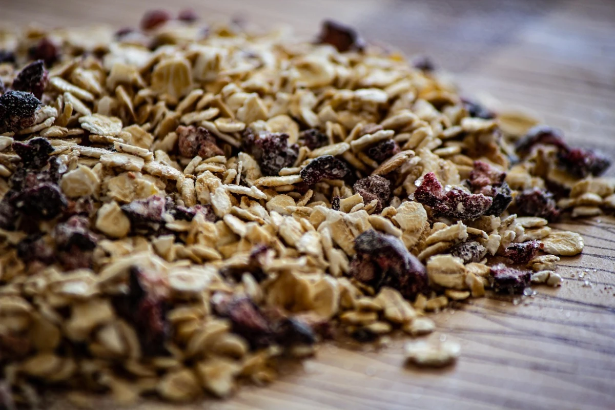 Zbliżenie na mieszankę płatków owsianych z suszonymi owocami, rozsypaną na drewnianym blacie