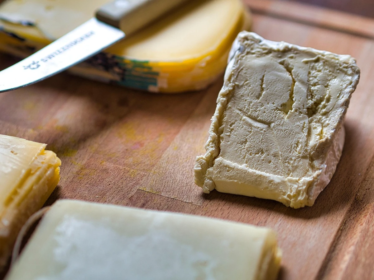 Zbliżenie na różne rodzaje serów na desce do krojenia, z widocznym nożem do sera