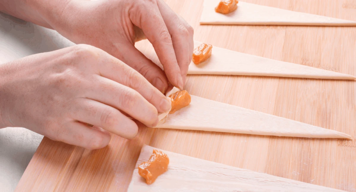 Zbliżenie na ręce kobiety zwijającej rogalik