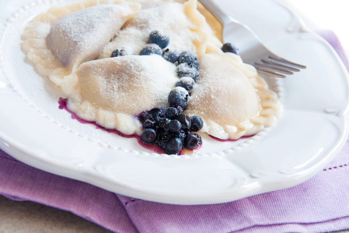 Pierogi z jagodami i białą czekoladą na białym talerzu